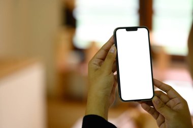 Sıcak bir mutfakta boş ekranlı akıllı telefonu tutan ellerinizi kapatın..