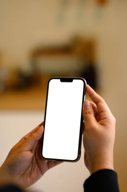 Mutfak arka planında cep telefonu kullanan eller.