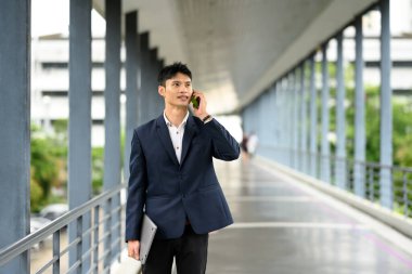 Kendine güvenen işadamı, modern yaya köprüsünde telefon görüşmesi yapıyor..