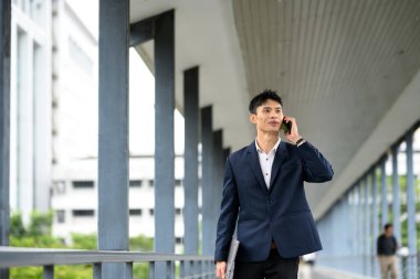 Şehirde yürürken kendine güvenen bir işadamı telefonda konuşuyor..