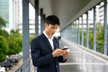 İş adamı, ara verildiğinde cep telefonundan mesajları okuyor..