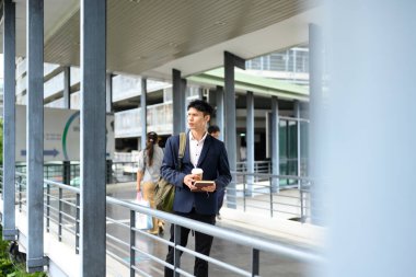 Elinde kahve ve defterle yaya köprüsünde duran bir iş adamı..