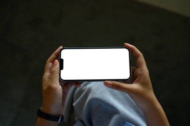 Boş beyaz ekran ile yatay yönelimde akıllı telefonu tutan eller.