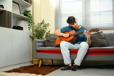 Sıradan bir erkek evde gitar çalışıyor, oturma odasında dinleniyor..