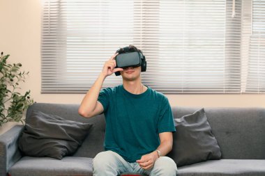 Sıradan bir adam evdeki kanepede sanal gerçeklik eğlencesinin tadını çıkarıyor..