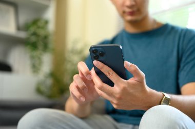 Parlak oturma odasındaki kanepede otururken akıllı telefon kullanan delikanlıya yaklaş..