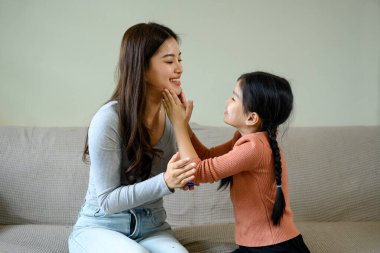Evde cilt bakımı yaparken annesinin yüzüne nemlendirici süren küçük bir kız...