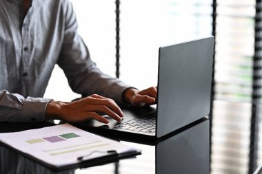 Masasında mali raporlar olan bir dizüstü bilgisayarda çalışan işadamlarına yakın durun..