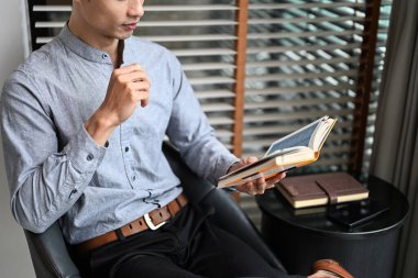 İnsanın kitap okuduğu modern bir odada rahat rahat oturduğu, doğal ışığın olduğu bir yere..