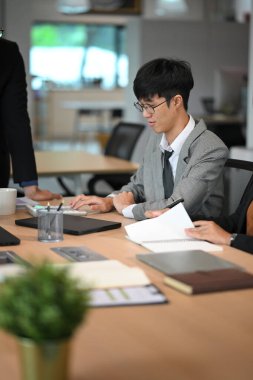 Odaklanmış işadamı verileri gözden geçiriyor ve ortak bir çalışma alanında hesaplamalar yapıyor.