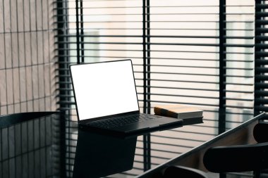 Modern çalışma alanı, dizüstü bilgisayarı ve şık bir ofiste pencere perdelerinin yanındaki parlak siyah masa üzerine kitap..