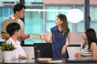 Takım üyeleri, modern bir ofiste kahve molası sırasında gayri resmi bir görüşme yapıyorlar..