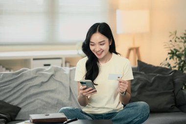 Dijital alışveriş ve güvenli işlemler için mobil bankacılık uygulaması kullanan neşeli bayan müşteri.