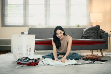 Ev işleri yapan bir kadın, evde temiz çamaşırları ayırıp katlıyor..