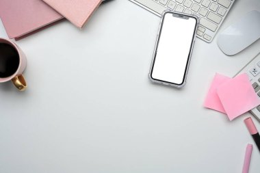 Akıllı telefonu, pembe defterleri, yapışkan notları ve beyaz masasında kahve fincanı olan en az kadınsı çalışma alanı..