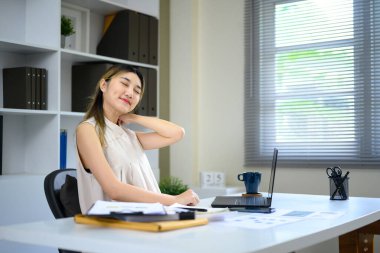 Yorgun bayan girişimci uzun saatler süren bilgisayar çalışmalarından sonra boynuna masaj yapıyor..