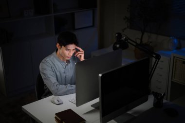 Odaklanmış işadamı gece geç saatlere kadar masa lambası altında bilgisayar başında çalışıyor..