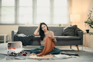 Çamaşır sepetiyle yerde oturan hayal kırıklığına uğramış kadın, evde çamaşır katlarken strese girdi..