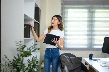 Parlak bir çalışma alanında çalışırken ofis dosyaları ve evraklarını yöneten kadın çalışan.