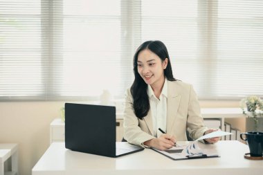 Dizüstü bilgisayar ve finansal belgelerle çalışan kendine güvenen bayan yönetici n blazer.