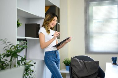 Modern çalışma alanında çalışırken belgeleri inceleyen neşeli genç girişimci.