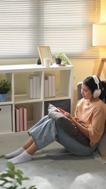 Müzik dinleyen ya da akıllı telefonuyla video izleyen mutlu genç bir kadın..