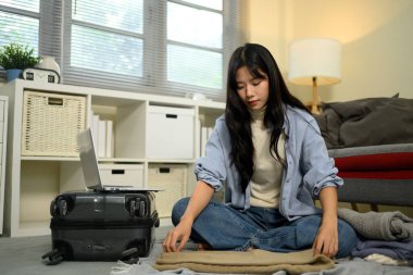 Genç bir kadın tatile hazırlanıyor, giysilerini dikkatlice bavula koyuyor..