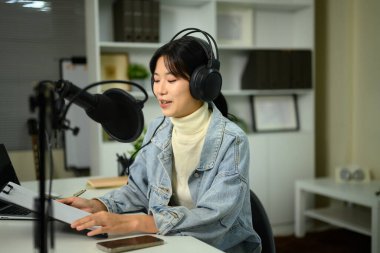 Canlı kayıt sırasında notlar okunurken mikrofona konuşan kadın podcaster.