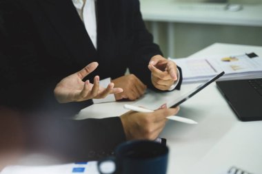 Ofiste tablet ve belgelerle strateji tartışması yapan iş profesyonellerini kapatın..