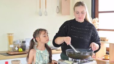 Küçük kız yemek yaparken meraklı ve dikkatli görünüyor..