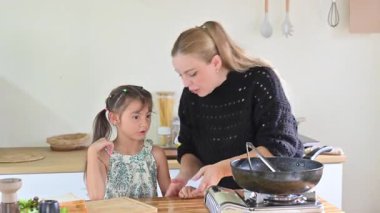 Anne ve kızı sıcak bir ev mutfağında birlikte kahvaltı hazırlıyorlar..