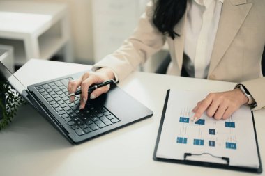 İş kadını dizüstü bilgisayarda çalışırken dosya ve diyagramlarla belgeleri analiz ediyor..