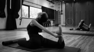 Esneklik eğitimi alan ve sakin bir şekilde gerilen bir kadının siyah beyaz görüntüsü..