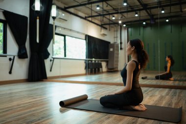 Evde yoga yapan genç bir kadın, paspasın üzerinde nöbet geçiren bir kadın, sakin bir stüdyoda meditasyon yapan bir kadın..