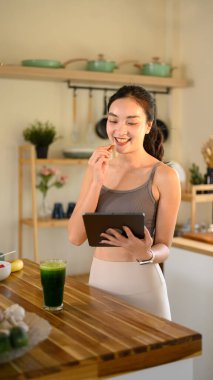 Mutfakta tarifli tablet kullanan genç bir kadın..