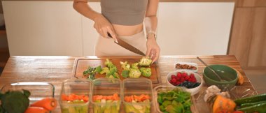 Brokoli doğrayan ve yiyecekleri öğünlere ayıran kadın hafta sonları kilo vermeye hazırlanıyor..