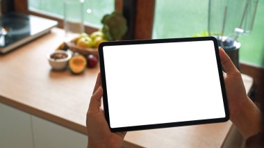 Modern mutfaktaki boş beyaz ekranlı dijital tableti tutan kişiye yaklaş.