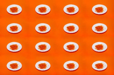 Turuncu arka planda beyaz bir tabakta ince dilimlenmiş havuçlarla kolaj.