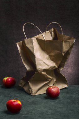 Still life with red apples and a paper bag