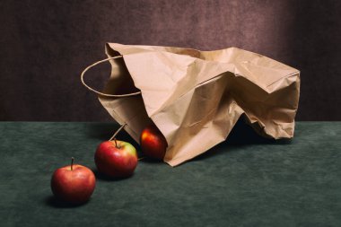 Still life with red apples and a paper bag