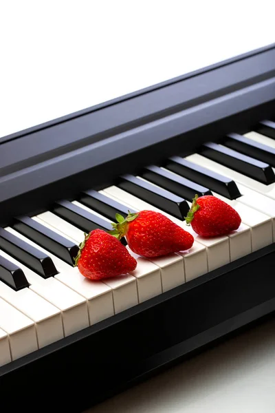 钢琴琴键上的三个成熟草莓 — 图库照片