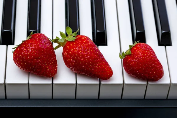 ピアノの鍵の上の3つの熟したイチゴ — ストック写真