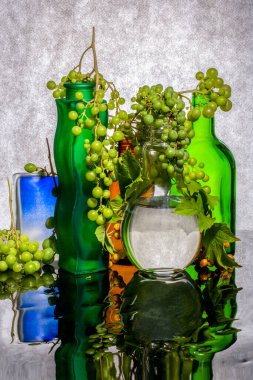 Renkli cam şişeler ve üzümlerle dolu bir hayat