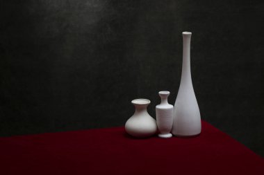 Kırmızı masa örtüsü olan beyaz vazolarla dolu bir hayat.