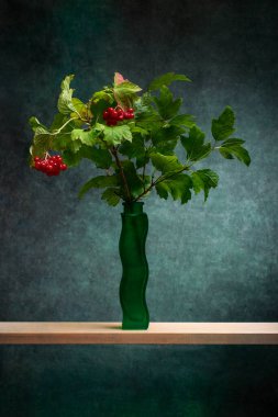 Yeşil bir vazoda kırmızı viburnum var.