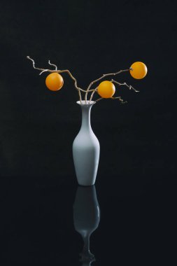 Beyaz vazoda turuncu toplarla dolu bir hayat.