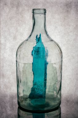 Gri arka planda şeffaf cam bir şişeyle