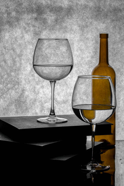 Still life with books, an empty bottle and glasses with liquid