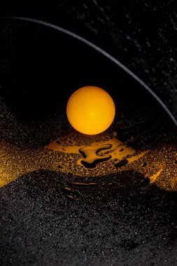 Yansıtıcı yüzeyde turuncu top ve su damlalarıyla soyut görüntü