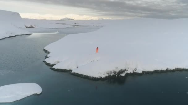 Muž Oranžovém Obleku Stojí Bílém Zasněženém Pobřeží Antarktidy Pohled Zasněžené — Stock video